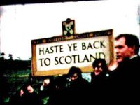 The Beatles beside a 'Haste ye back to Scotland' sign, October 1964